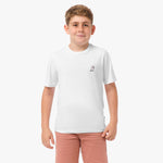 Front view of the boy wearing the white T-shirt with a small embroidered logo on the chest, paired with pink shorts.