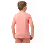 Rear view of a boy wearing the light pink t-shirt, standing with his hands behind his back.