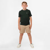 Full-body view of a boy wearing the black t-shirt and beige shorts, standing with his hands in his pockets and legs slightly apart.