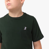 Close-up front view of a boy wearing the black t-shirt with a small white embroidered logo on the chest.