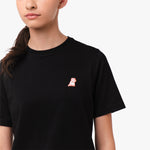 Close-up of the chest area of the black T-shirt, featuring the small embroidered logo.