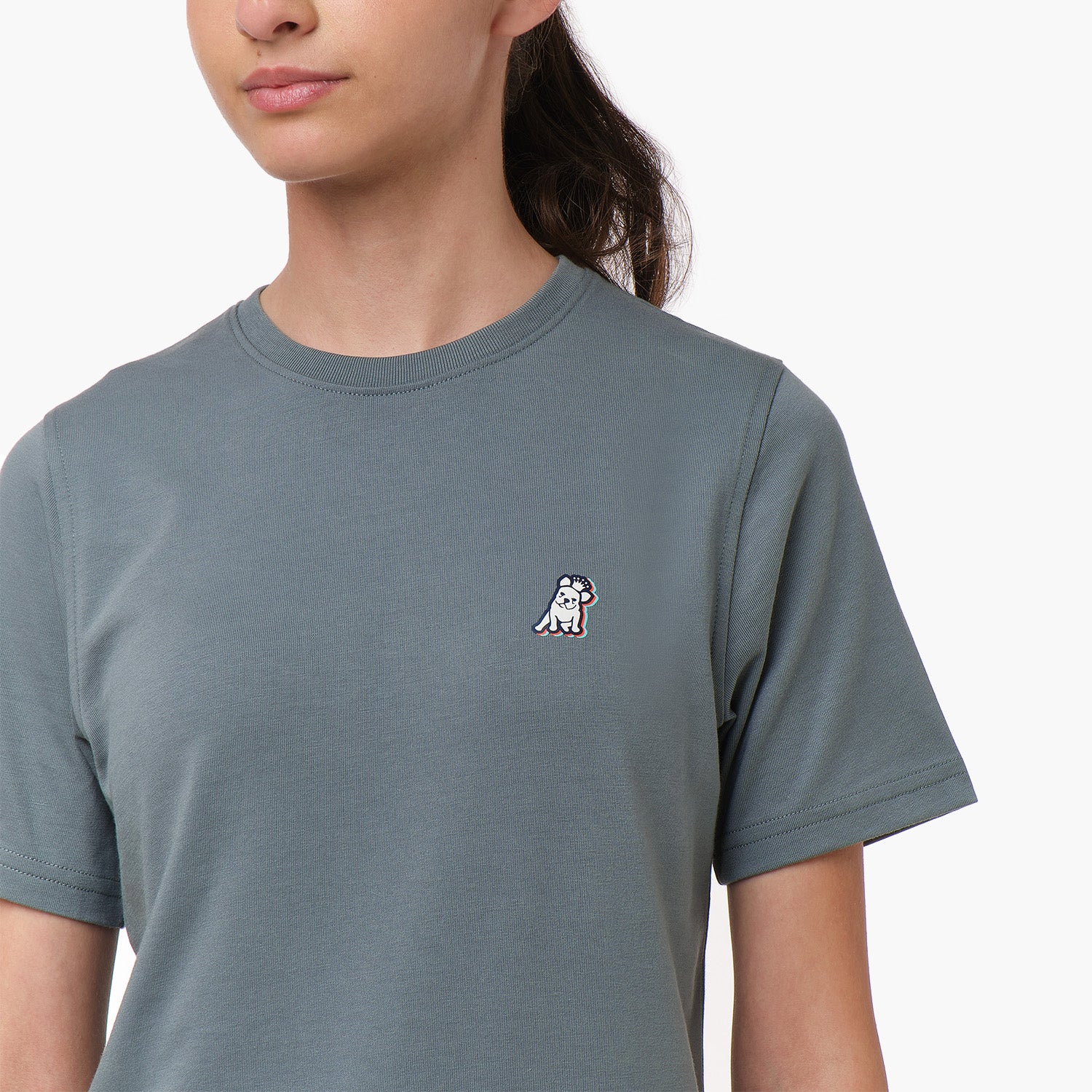 Close-up front view of a woman wearing the gray t-shirt with a small embroidered logo on the chest.