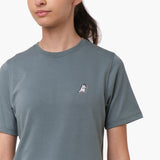 Close-up front view of a woman wearing the gray t-shirt with a small embroidered logo on the chest.