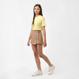 Full-body view of a girl wearing the light yellow t-shirt and light brown skirt, standing with one hand on her hip.