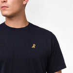 Side view close-up of the collar and chest of the navy blue t-shirt: A detailed side profile showing the crew neck collar and the small embroidered dog logo on the left chest.