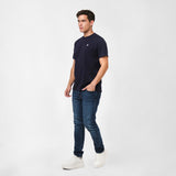 Man wearing a navy t-shirt and jeans on a white background