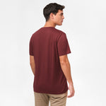 A side view of the man wearing the maroon t-shirt, with his back turned.