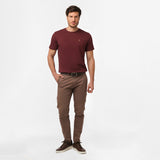 A full-body shot of the man in the maroon t-shirt and brown pants, standing casually with his hands in his pockets.