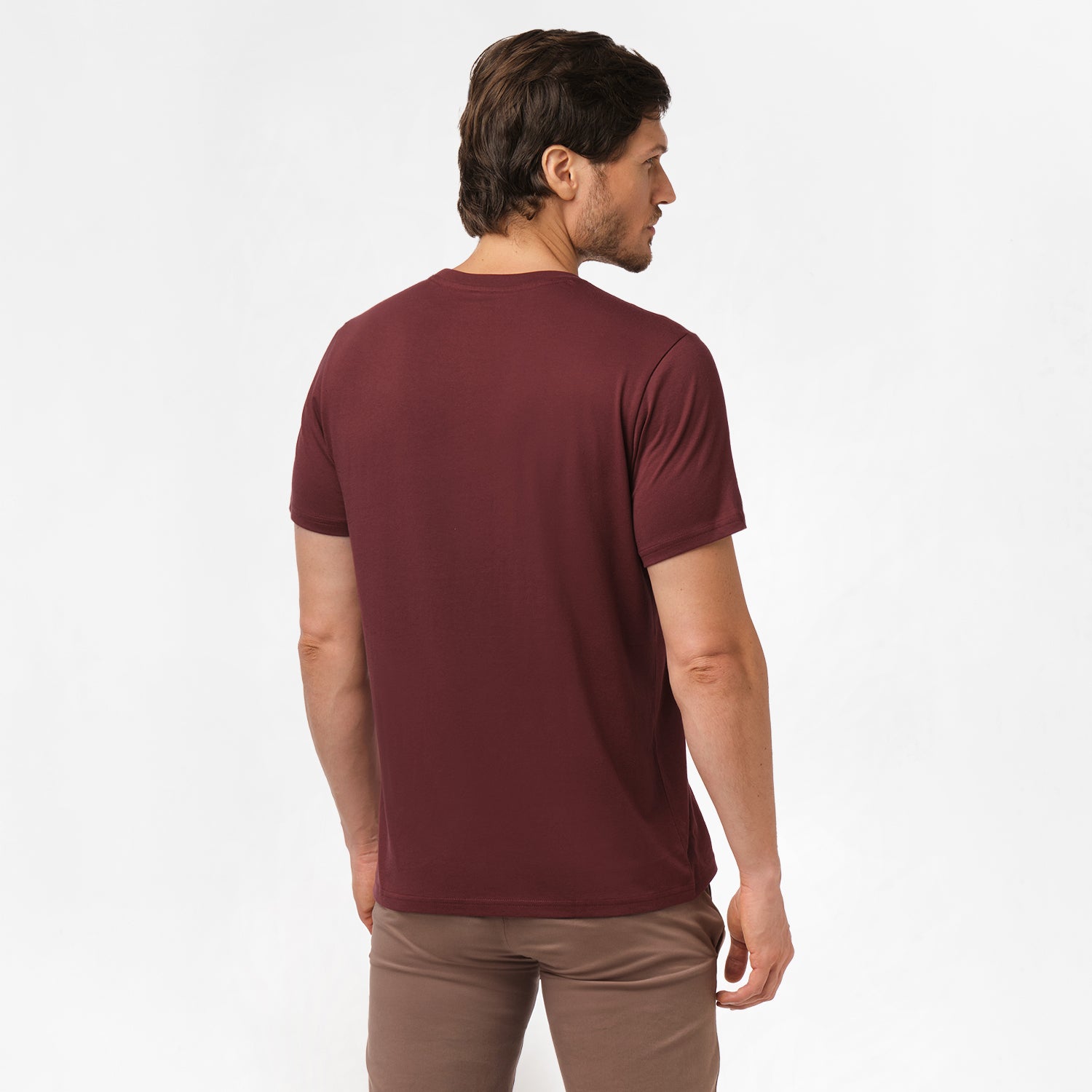 A side view of the man wearing the maroon t-shirt, with his back turned, showing the fit of the t-shirt and brown pants.