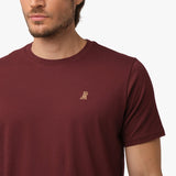 A close-up of the chest area of the maroon t-shirt, highlighting the small embroidered graphic of a dog.