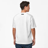 Back view of the model wearing the white t-shirt, showing a black rectangular tag below the collar.