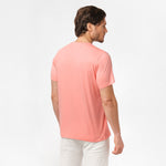 Back view of the man wearing the light pink t-shirt, standing with his arms at his sides, paired with white shorts.