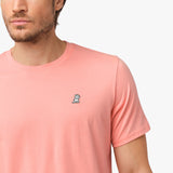 Close-up of the upper chest area of the light pink t-shirt, focusing on the small embroidered animal logo near the neckline.