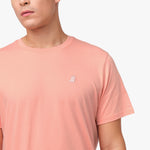 Close-up of the upper chest area of the light pink t-shirt, focusing on the small embroidered animal logo near the neckline.