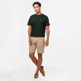 A full-body image of the man wearing the dark green t-shirt and beige shorts, standing in a relaxed posture with one leg slightly bent.