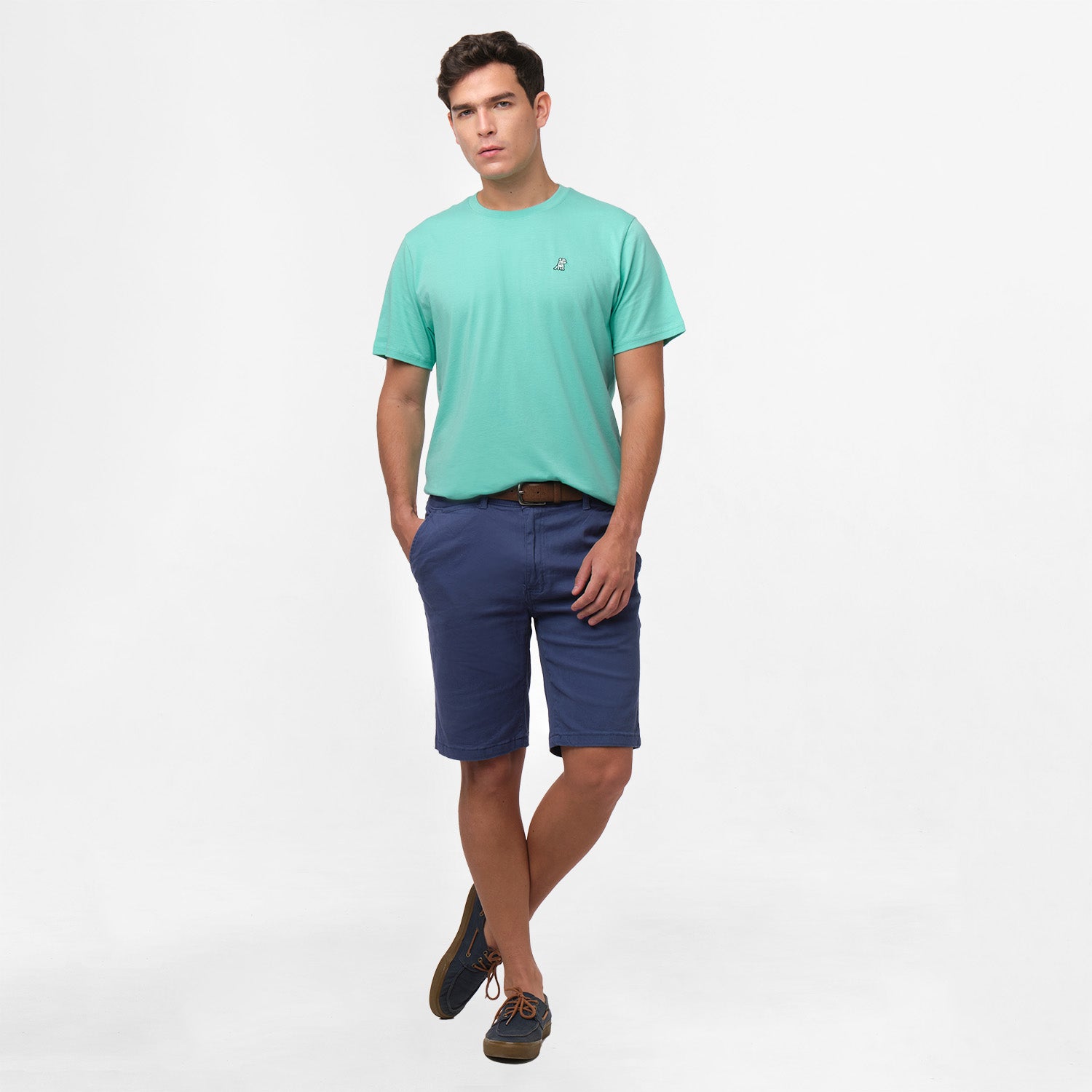 A full-body image of the man wearing the mint green t-shirt and navy blue shorts, standing in a relaxed posture with one leg slightly bent.