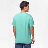 Back view of the man wearing the mint green t-shirt, standing with his arms at his sides, paired with navy blue shorts.