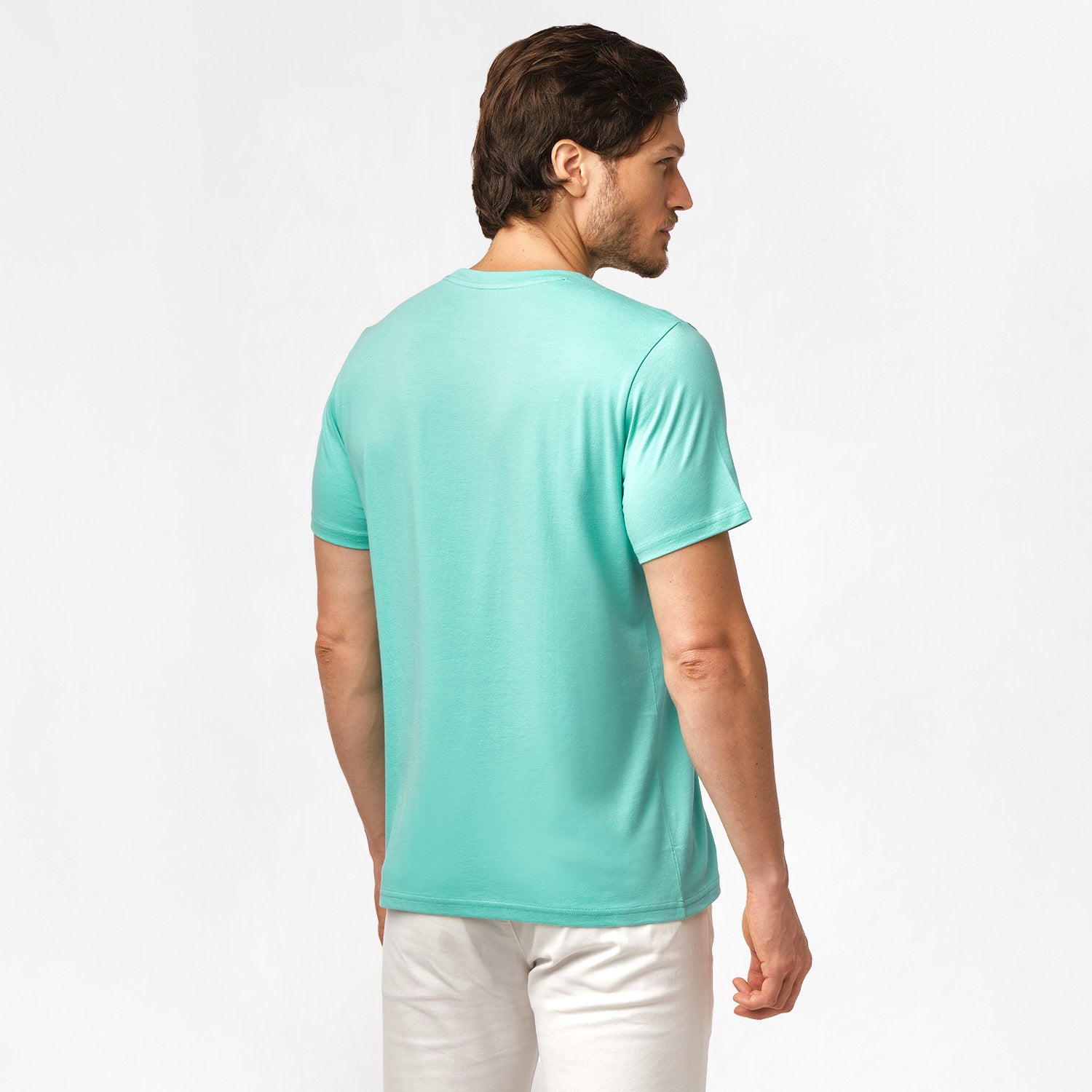 Back view of the man wearing the mint green t-shirt, standing with his arms at his sides, paired with white shorts.