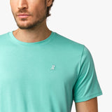 Close-up of the upper chest area of the mint green t-shirt, focusing on the small embroidered animal logo near the neckline.