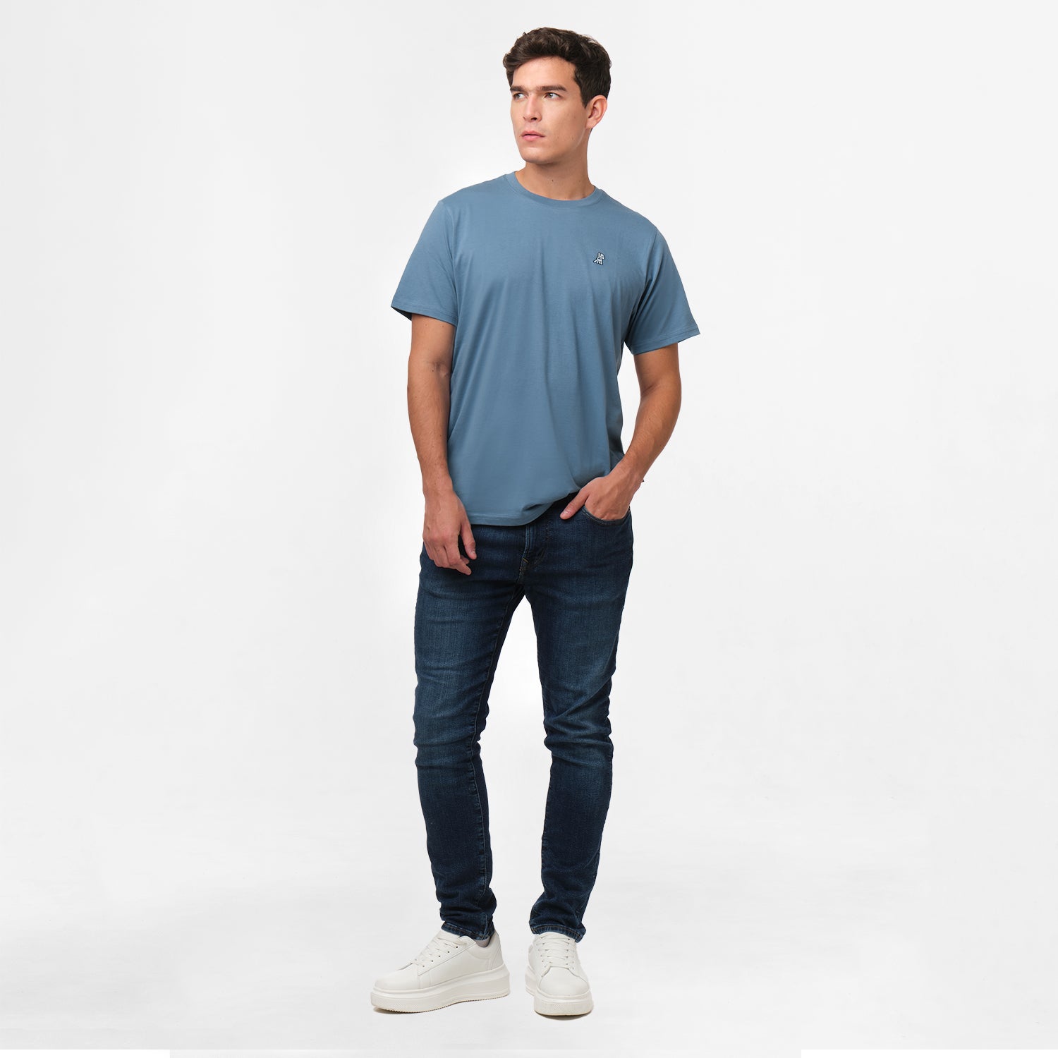 A full-body image of the man wearing the blue t-shirt and dark blue jeans, standing in a relaxed posture.