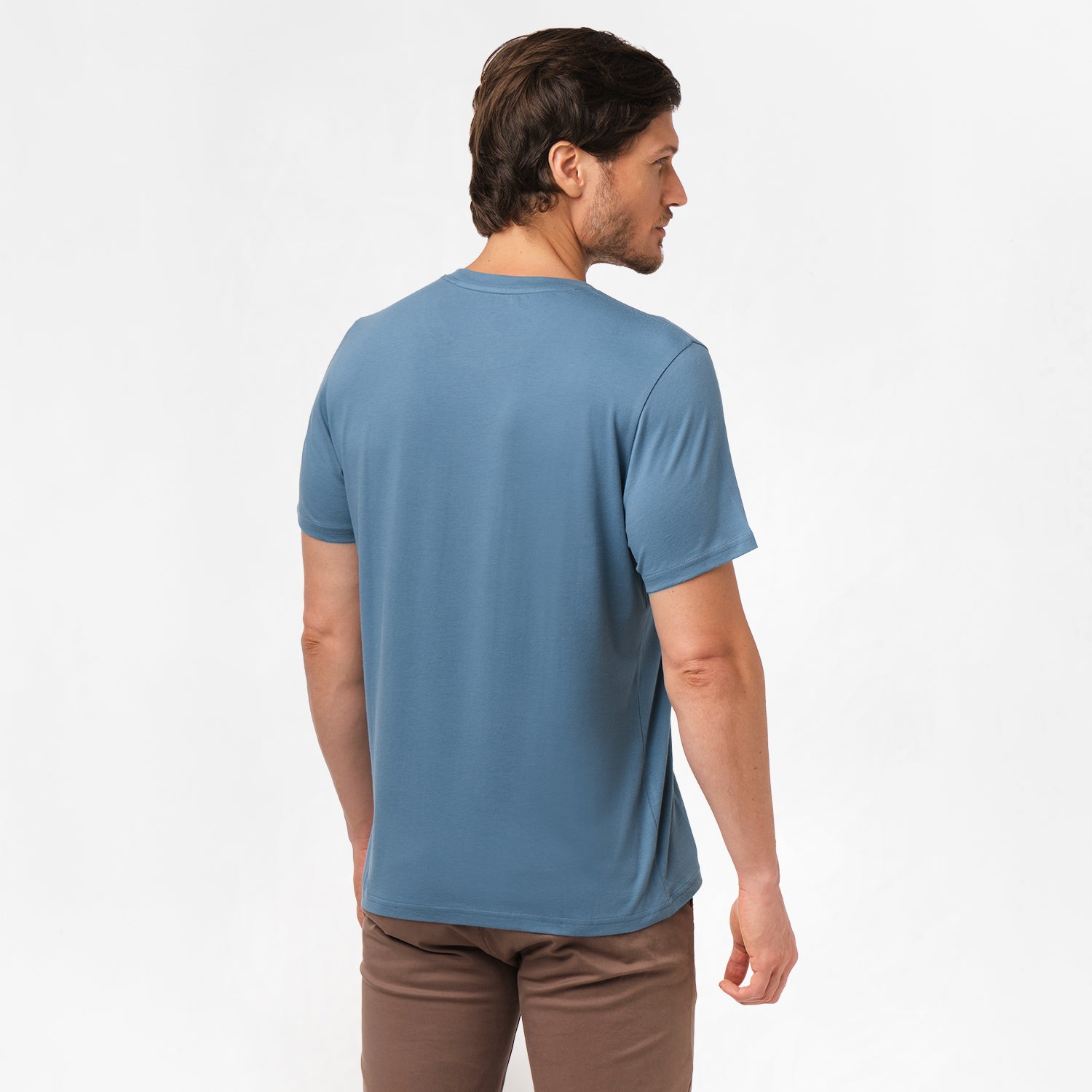 Back view of the man wearing the blue t-shirt, standing with his arms at his sides, paired with brown pants.