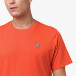 Close-up of the upper chest area of the orange t-shirt, focusing on the small embroidered animal logo near the neckline.