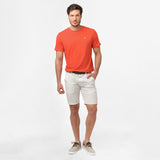 A full-body image of the man wearing the bright orange t-shirt and white shorts, standing in a relaxed posture.