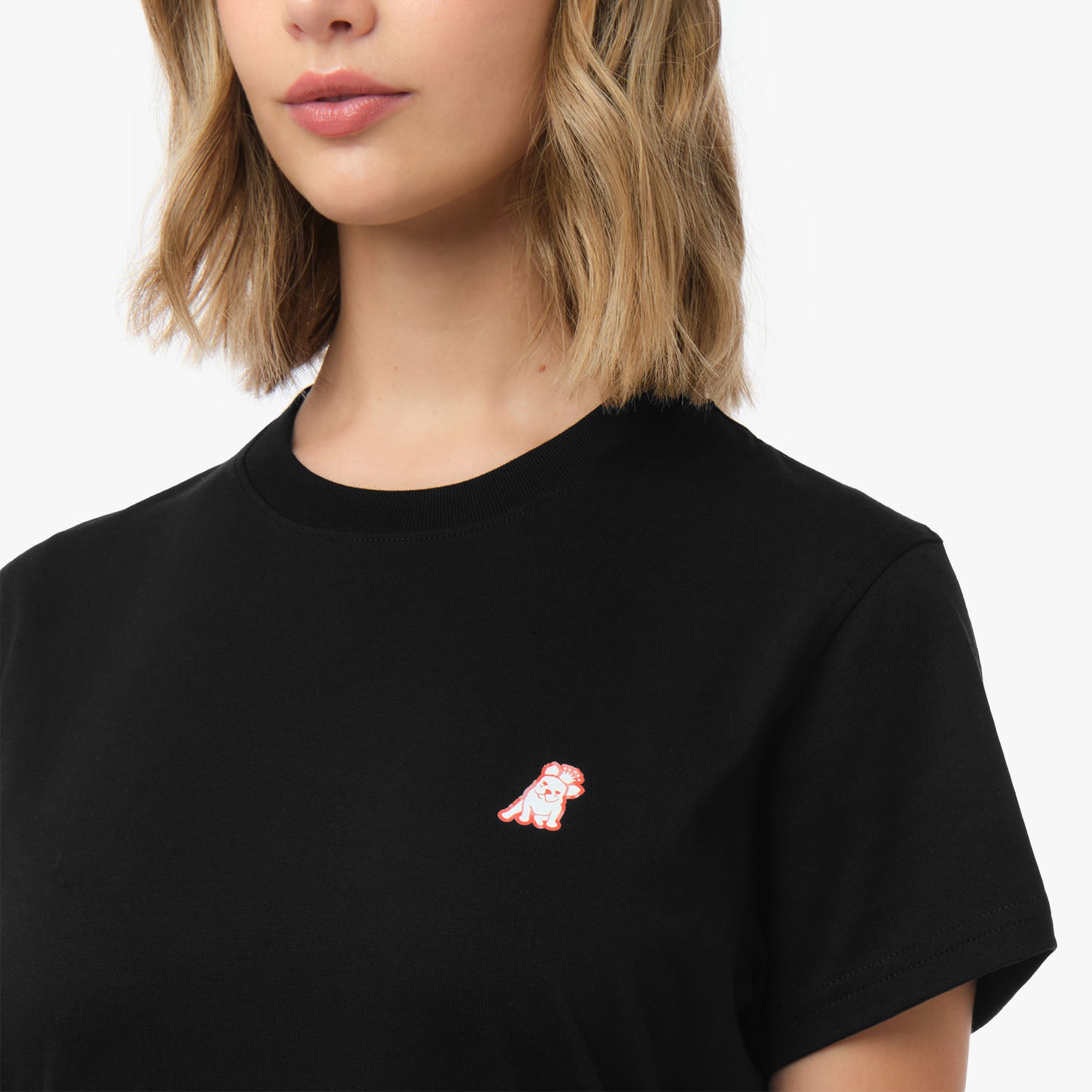 Close-up of the woman's chest area, highlighting the small embroidered logo on the black t-shirt.
