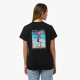 Rear view of a woman wearing a black t-shirt with a large graphic of a beach scene featuring stacked lifeguard chairs and a dog.