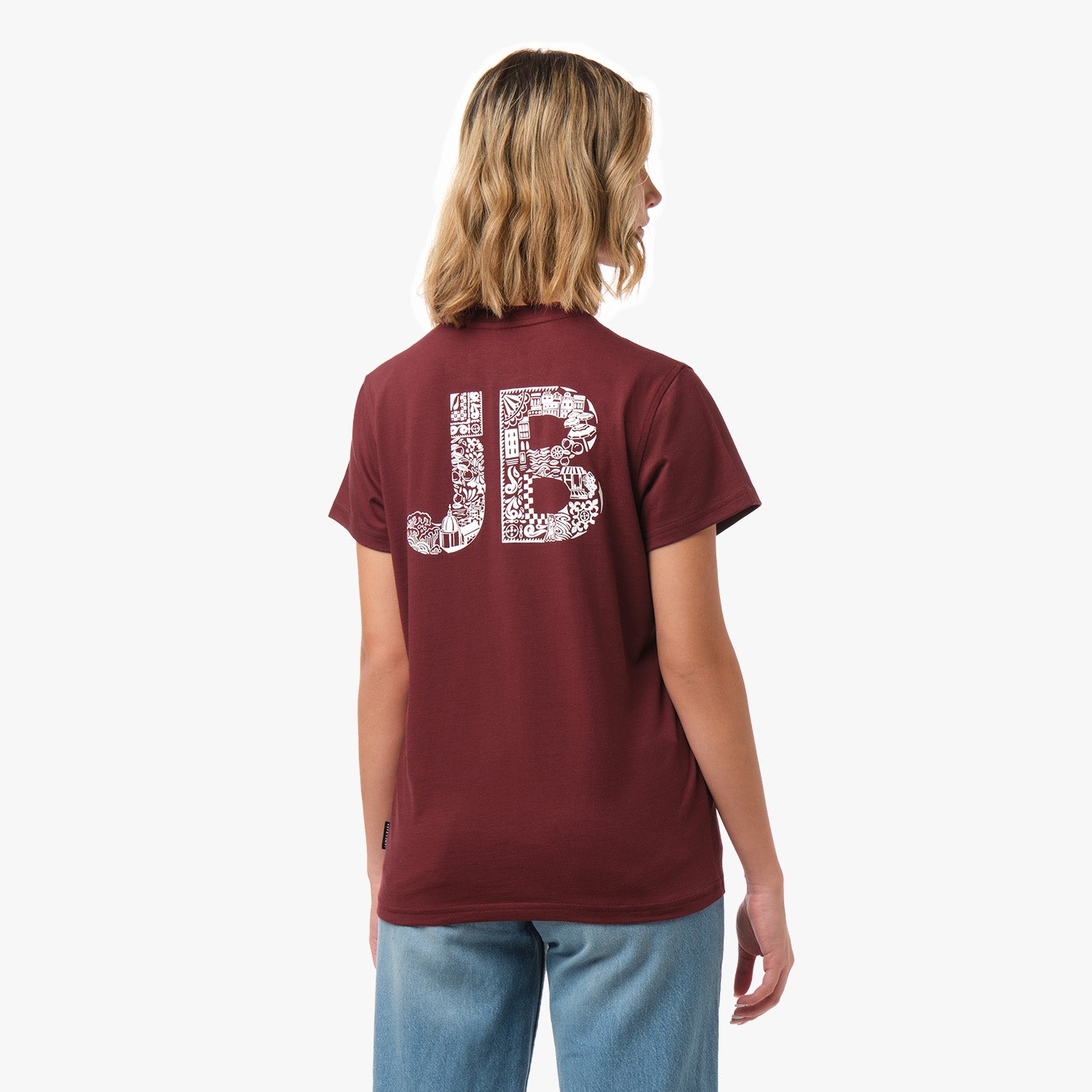 Rear view of a woman wearing a burgundy t-shirt with a large "JB" graphic in a white intricate pattern.