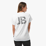 Rear view of a woman wearing a white t-shirt with a large "JB" graphic in a black intricate pattern.