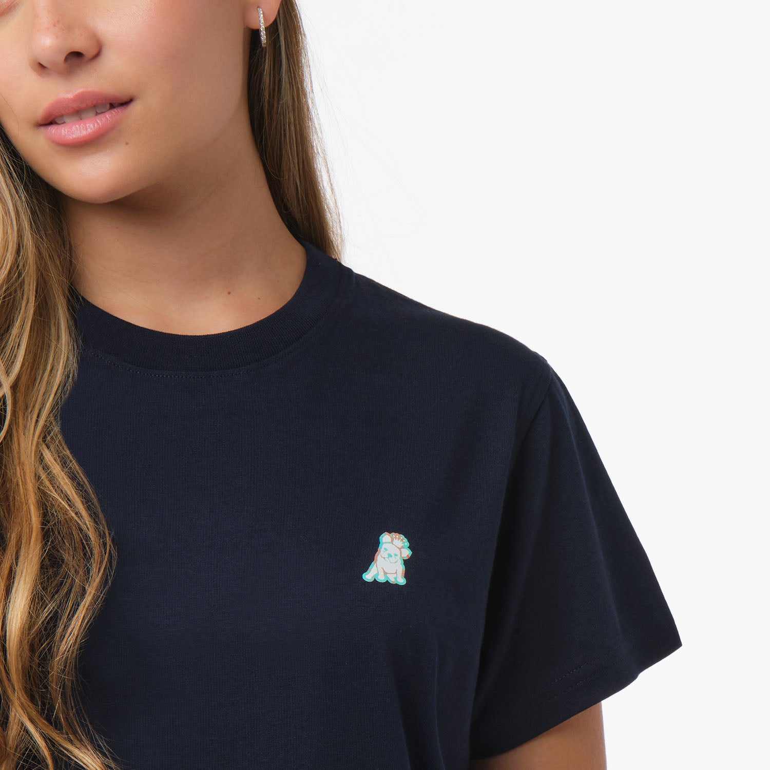 Close-up of the woman's chest area, highlighting the small embroidered logo on the navy blue t-shirt.