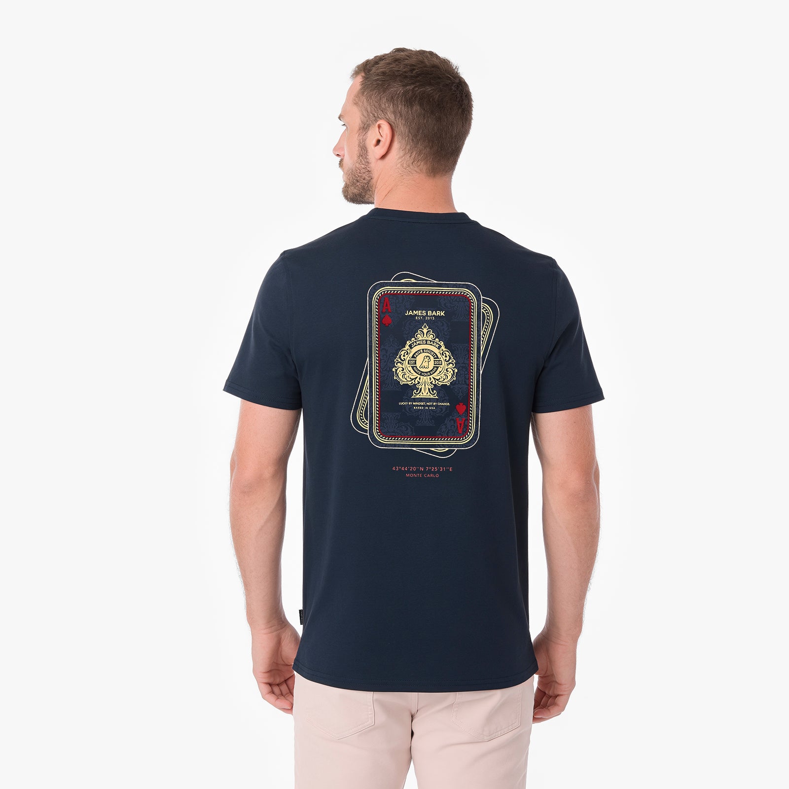 A man viewed from the back wearing a navy blue T-shirt with a large playing card graphic on the back