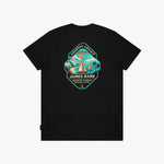 A black T-shirt with a large, colorful vintage-style graphic on the chest. The graphic features a teal and orange shield design with sailboats, mountains, and the text 'COASTAL LEGACY' and 'JAMES BARK'.