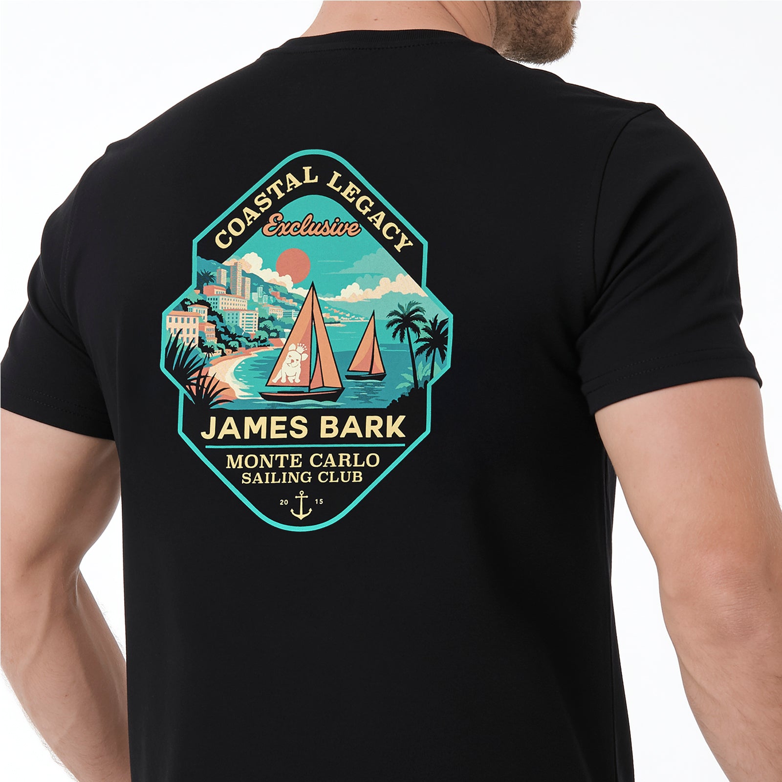 A man wearing a black T-shirt with a large, colorful vintage-style graphic on the chest. The graphic features a teal and orange shield design with sailboats