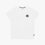 A white T-shirt with a small circular crest printed on the left chest. The inner collar features a contrasting navy blue trim, and a small black tag is visible near the bottom-right hem.