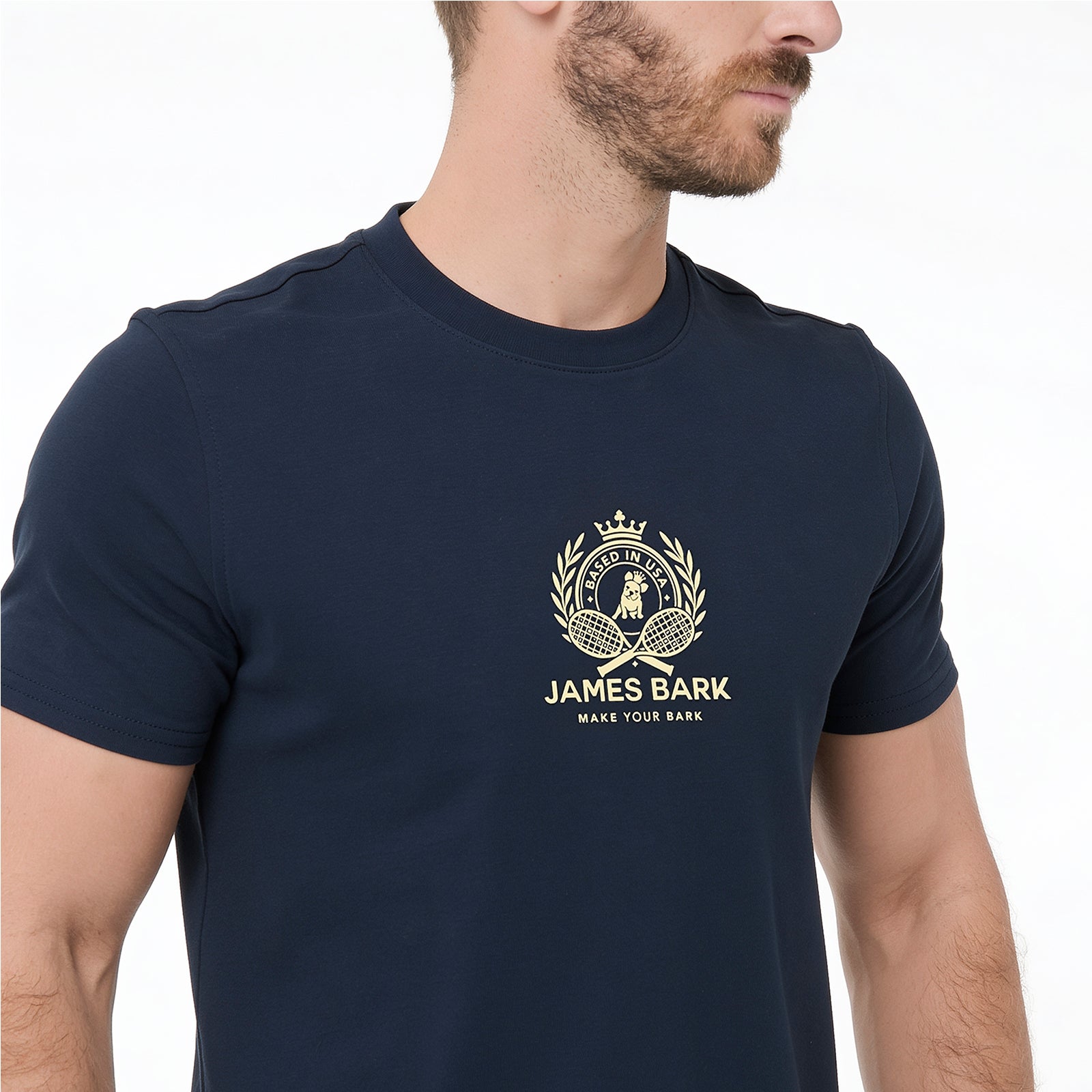 A man wearing a navy blue T-shirt with a gold James Bark logo printed on the chest