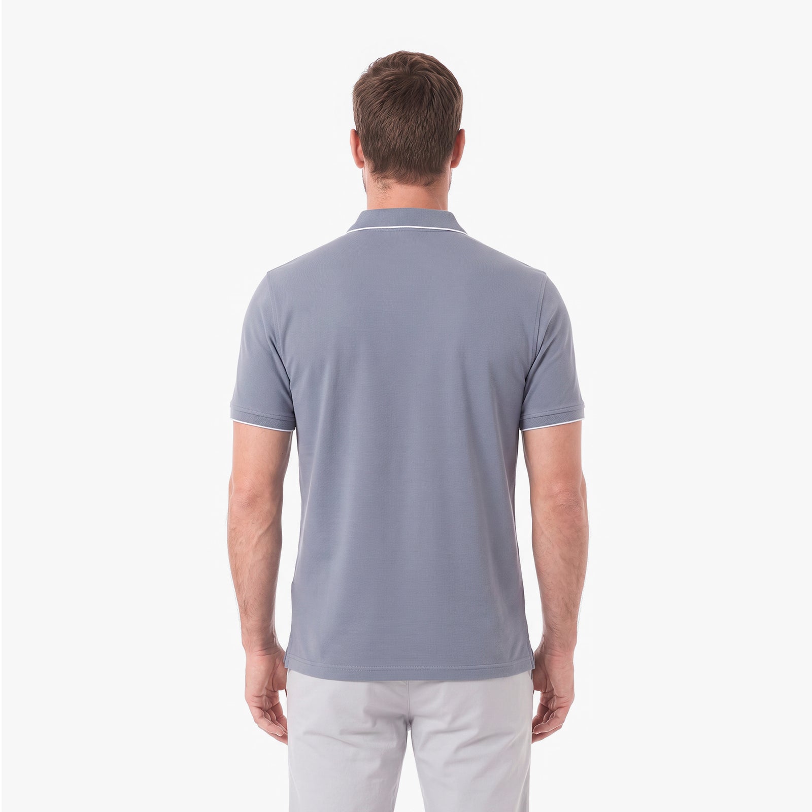 A man viewed from the back wearing a light gray short-sleeve polo shirt with thin white piping on the collar and sleeve cuffs