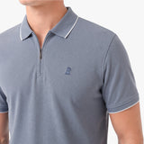 A close-up of a man wearing a slate blue short-sleeve polo shirt with a half-zip collar and white piping trim.
