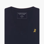 Close-up of a folded navy blue v-neck t-shirt, showing the printed inner neck label "JAMES BARK, MAKE YOUR BARK, PIMA COTTON, MADE IN PERU, S" and a small yellow and black embroidered dog logo on the left chest