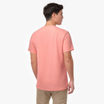 Male model showing the back of a peach/coral men's crew neck t-shirt and tan chino pants, shot on white.