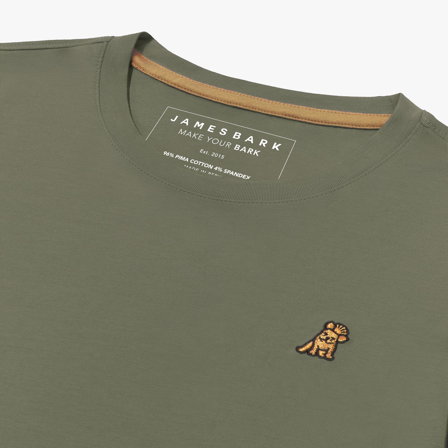 Close-up angled view of the inside collar area of the olive green crew neck t-shirt laid flat. Shows the ribbed neckline, gold neck tape, the printed "JAMES BARK" brand tag, and the gold/yellow embroidered dog logo on the chest