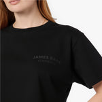 Close-up of the black 'James Bark Elements' logo printed on a black cotton cropped t-shirt.