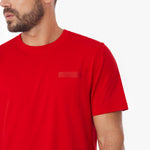 Close-up of a male model wearing a red James Bark t-shirt, showing the embossed logo patch