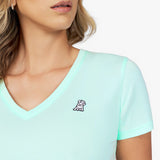 Close-up detail of the mint green v-neck t-shirt neckline, showing the fabric texture and the small white embroidered dog logo on the left chest