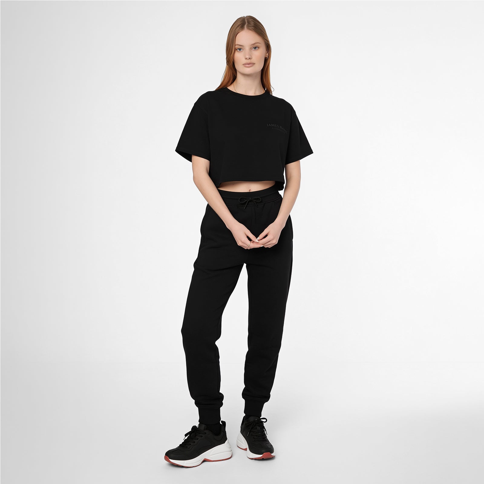 Full-length shot of a woman modeling a black James Bark Elements cropped t-shirt and joggers set.