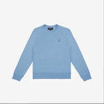 A light blue crewneck sweatshirt laid flat on a white background. It has long sleeves, ribbed cuffs, and a ribbed hem. A small embroidered logo of a dog is positioned on the left chest area. The neckline features a black label with white text. The fabric appears to be soft and comfortable