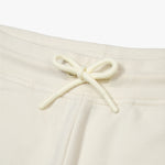 Close-up of the drawstring detail on an off-white jogger pant, showing the elastic waistband and tied bow for adjustable fit