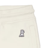 Close-up of an off-white jogger pant showcasing an embroidered playful dog design and a side pocket detail