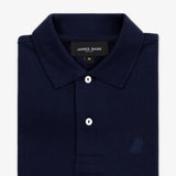 Close-up of the collar of the navy blue polo shirt, showing the label and a button.